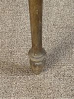 Close-up detail of the turned wooden leg showing wear and carved decorative foot.
