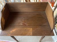 Top view showing the walnut writing surface with raised back and side panels, surface shows age wear and some marks.