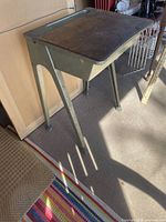 Aluminum school desk with angled legs and wood top, side view showing storage compartment