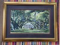 Framed watercolor print showing the full artwork and the gold frame on a multi-colored woven background.