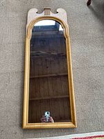 Full view of the tall vintage wall mirror showing the maple wood frame and reflective glass surface, with a carved top section typical of Chippendale design.