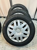 Four Michelin tires stacked with front tire showing clean silver Toyota wheel cover in perfect condition.