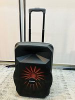 Front view of Sylvania SPA122 speaker showing black mesh grille with radial red light pattern and logo.