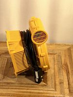 Side view showing yellow fan housing, air intake vent grill, and wrapped power cord with control box.