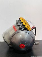 Side view of Dyson Big Ball dustbin canister showing grey plastic body and yellow top section