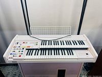 Front angled view of electric home organ showing dual keyboards, control panel with buttons, and foot pedals.