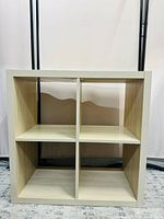 Front view of the white stained oak IKEA KALLAX shelf unit, showing 4 square compartments with no visible damage on upper surfaces.