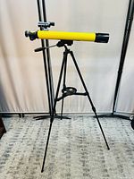 Full side view of telescope mounted on tripod with yellow tube and black fittings