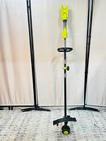 Full length view of the Ryobi string trimmer standing upright, showing the overall design and cutting head with guard.