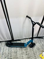 Side view of blue Planet Evo scooter showing blue frame, black grip handlebars, and front and rear wheels on a carpeted floor.
