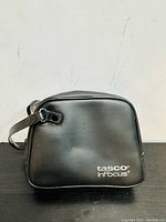 Black zippered travel case with 'tasco InFocus' logo visible on front.