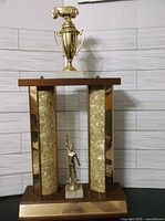 Full view of the vintage 1964 automobile trophy showing wood and gold-tone metal columns with figurines.