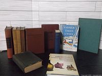 Lot of 11 various antique and vintage hardcover books arranged on table showing color, binding style and size variations