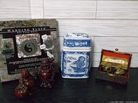Photo showing all items: hanging Yin Yang slate, two Buddha figurines, blue and white ginger jar, and boxed decorative boarding balls