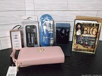 Assorted new items displayed together: pink case, earbuds, rings, tool case, photo album