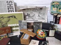 Overview of various vintage and antique items including postcards, domino set, small clown container, bottle, and newspaper clippings.