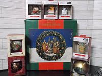 Image showing Hallmark ornaments including Harry Potter figures, Star Wars R2-D2, on top of the CAROLER wreath box, with additional Star Wars Yoda and Death Star ornaments to the right and left of the box.