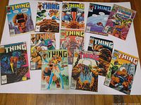 Full view of 13 'The Thing' comic books spread on a surface, showing different cover arts and titles within the collection.