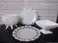 Three milk glass pieces including round pierced edge plate, kitty cat plate with pierced edge, and square pedestal rose dish.