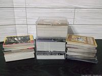 Four stacks of assorted non-sport trading cards on a surface, showing thickness and size variations