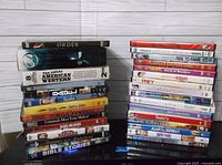 Stack of approximately 29 DVDs with visible mixed titles and cases