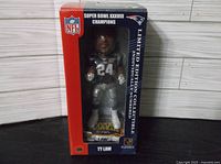 Photo of the unopened box containing the Ty Law figurine, showing front view with clear window, NFL and Super Bowl XXXVIII Champions branding