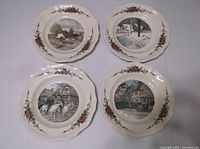 Four vintage decorative plates arranged in a 2x2 layout showing different village scenes and floral border patterns.