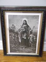 Full view of the lithograph showing Jesus holding a lamb surrounded by sheep in a pastoral scene, framed behind glass.