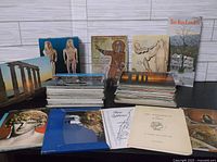 Overview of the vintage postcards collection showing multiple stacks of postcards, some featuring Greek statues, columns, and cultural mosaics, with booklets laid out in front.