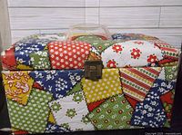 Closed view of colorful patchwork vintage sewing box with metal latch and clear handle