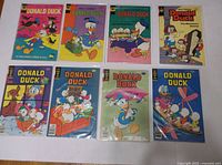 Eight vintage Donald Duck comic books laid out, displaying colorful covers with various Donald Duck scenes and characters.