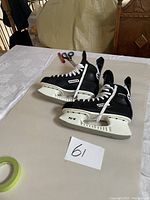 Side view of Bauer black and white size 10 ice hockey skates with white laces, showing branding and blade holder.