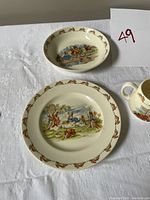 Set of Bunnykins child dishware on white cloth, showing plate and bowl with rabbit illustrations and border pattern
