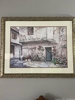 Full view of framed print showing rustic European street scene with bicycle and flowers under window.