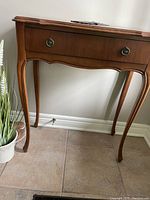 Full view of the light/medium oak hallway table with a drawer, showing curved legs and minor wear.