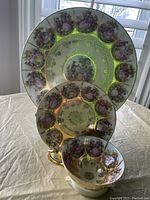 Cup, saucer, and plate displayed upright showing decorative patterns and gold trim.