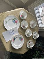 Top view of 6 teacups with saucers and 2 plates, showing floral pattern on white china.