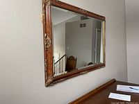Full view of the mirror showing its placement on a wall above a table indoors.