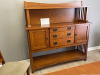 Full front view of mission style oak buffet showing two doors, three center drawers, bottom shelf and top display ledge