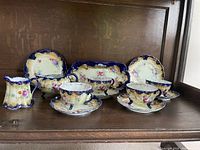 Full set arrangement showing 4 cups with saucers, creamer, sugar bowl, 2 sandwich plates, salt shaker, and teapot.