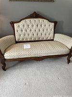 Full view of the antique Queen Anne style sofa showing the wooden carved backrest and patterned upholstery, seating and arms.