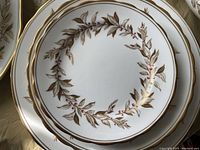 Close-up photo showing the intricate almond willow pattern and gold trimming on stacked plates.