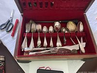 Top view of the silverware set with varied forks, spoons, and knives arranged in the red velvet-lined box.