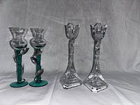 Two sets of candle holders: one set green with serpent design, one set clear with triangular flower top