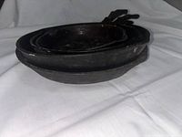 Stacked view of four cast iron frying pans showing thickness and depth