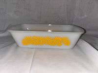 Side view of white loaf pan with yellow daisy flower design.