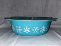 Side view showing turquoise blue casserole dish decorated with white snowflakes.