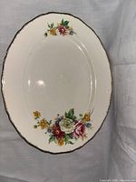 Top-down view of the oval serving platter showing floral patterns and gold trimmed scalloped edge.