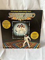 Front cover of the Saturday Night Fever soundtrack showing the logo, disco floor artwork, and photo of the Bee Gees band members