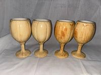 Four ceramic tulip style wine goblets with rounded bowl and arched relief pattern in peach-orange-tan glaze